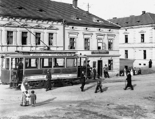 Motorový vůz evid. č. 20 na konečné ve Škvrňanech. Vynikající fotografie, díky které se podařilo objasnit několik důležitých detailů v provedení linkové orientace, vybavení stanoviště řidiče, provedení nástupních dvířek, apod. Fotografie pochází ze sbírek ZČM, skleněný negativ 13 × 18 cm, sign. NMP 3093. Snímek byl pořízen neznámým fotografem v období 1905—10.
