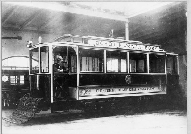 Tovární snímek vozu evid. č. 20. Fotografie napovídá, jak vypadaly prostory ve výrobním závodě firmy Brožík. Z hlediska vozu je zajímavé použití ochranného koše proti přejetí amerického typu. Šlo patrně o zkoušku. Velmi pravděpodobně nebylo toto ochranné zařízení v praxi používáno. Deskový ochranný rám kolem podvozku na voze není vůbec namontován.