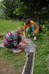 budování zahradního kolejiště je práce i zábava pro celou rodinu. Na snímku úprava štěrkového lože traťového svršku u stavědla Západ.