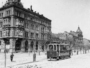 Motorový vůz evid. č. 8 v původním stavu jedoucí po Ferdinandově třídě (v prostoru Radeckého náměstí) směrem na Bory. Snímek byl pořízen v letech 1899—1900. Skleněný negativ formátu 11,9 × 16,6 cm, sbírky ZČM, sign. NMP 622. Výřez.