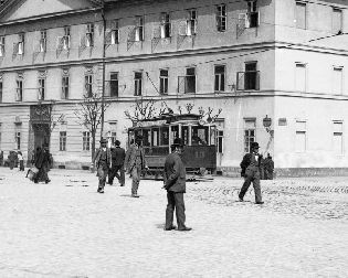 Motorový vůz evid. č. 13 v původním stavu u kasáren na rohu Palackého třídy a Štěpánových sadů. Snímek dobře zachycuje pouliční atmosféru v tehdejší Plzni. Pozornosti neujde např. naprostá absence člověka bez pokrývky hlavy. Fotografie byla pořízena přibližně v období 1902—06. Sbírky ZČM, sign. 641. Skleněný negativ formátu 13 × 18 cm. Výřez.